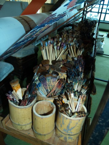 Many brushes standing in wooden pots at a dyeing workshop
