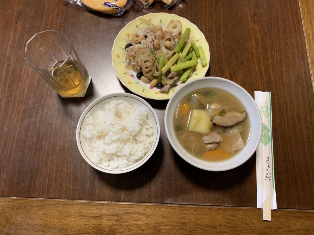 A set dinner of rice, a bowl of soup with meat and vegetables, a stir-fry with green vegetables and a glass of tea