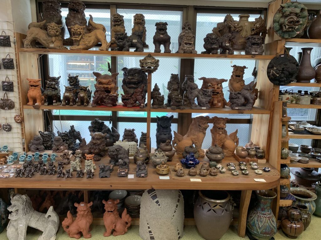Wooden shelves of shisa figures, vases and bowls in a pottery shop in Naha