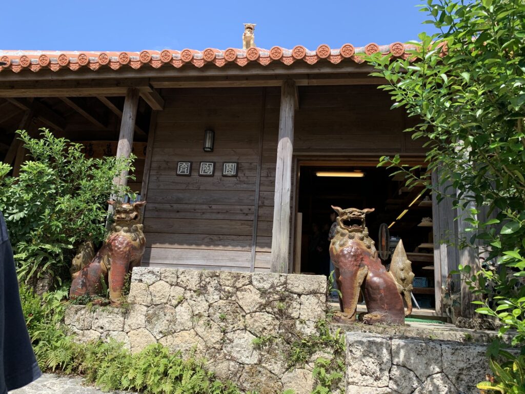 A pair of shisa guarding the entrance of a red-tiled pottery shop in Naha